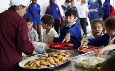 أطفال يتسلمون وجبة في مدرسة في لندن. أرشيف رويترز